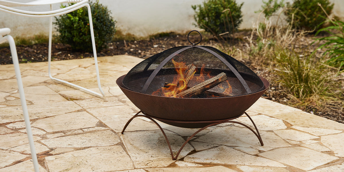 Glow Tuscany 55cm Weathering Steel Fire Pit GLOW2403 being used in a patio setting