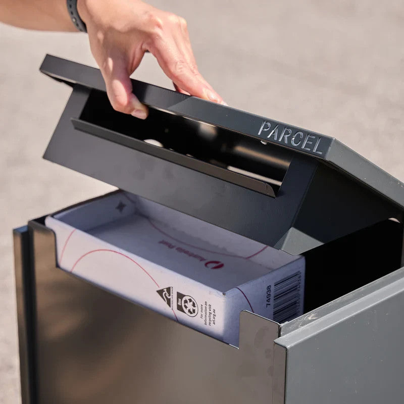 Empire Parcel Letterbox in grey steel with a hand lifting the hinged lid, parcel visible underneath