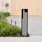 Swift Letterbox in grey installed in a garden bed beside a paved driveway, angled front view