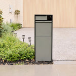 Zephyr Parcel Letterbox in charcoal steel installed beside a garden bed at the end of a paved driveway