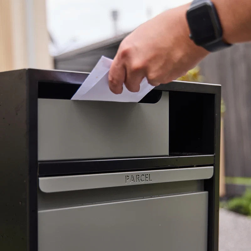 Zephyr Parcel Letterbox in charcoal steel, close up of a hand posting a letter through the marked parcel slot