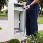 Zip Parcel Letterbox in white with the door open and a person standing beside it near a front fence.