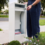 Zip Parcel Letterbox in white with the front door open, a person standing beside it on a garden path.